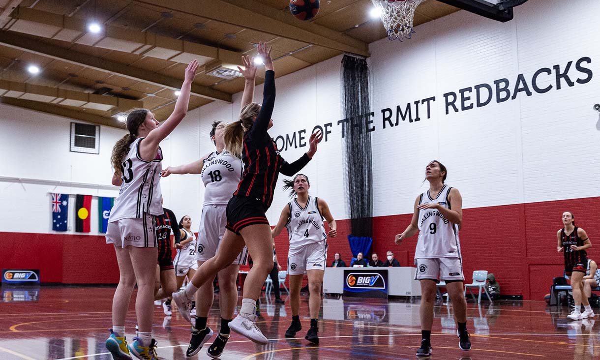 Basketball athletes from opposing teams compete for the ball