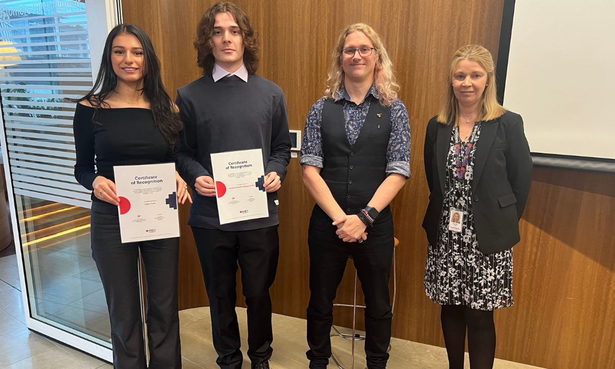 2 women and 2 men pose standing side-by-side, 2 of them are holding certificates.