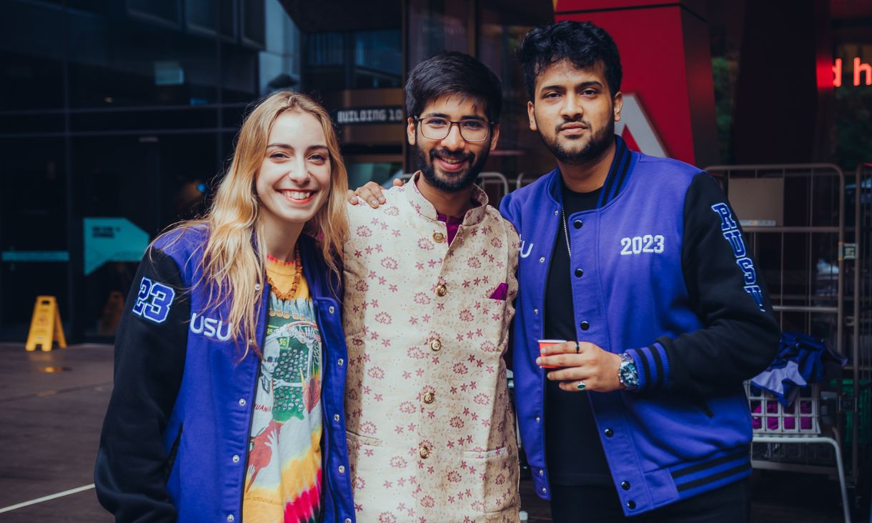 Three RMIT students including RUSU President Beth Shegog standing together looking towards camera smiling