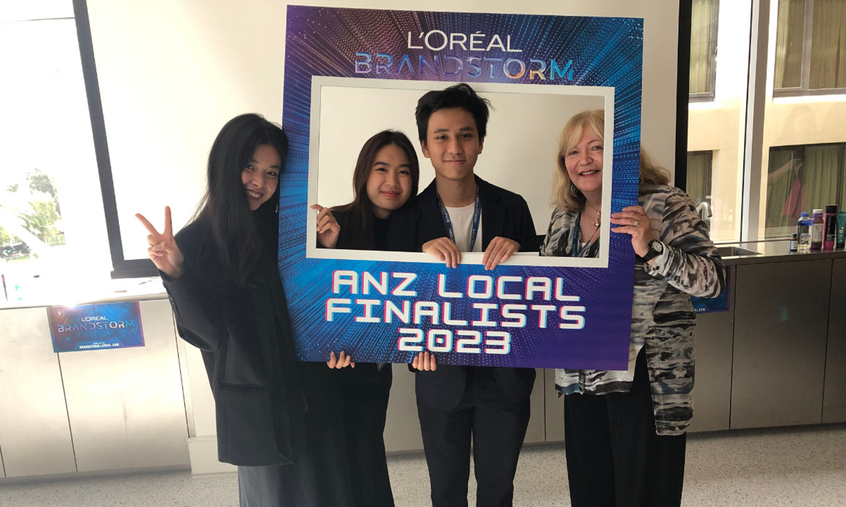 Four people behind cardboard cutout photo frame