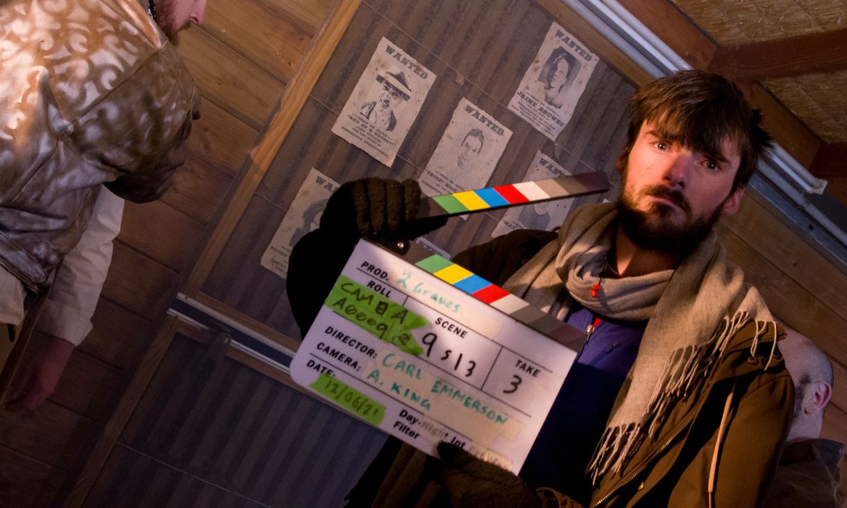 Young male student holding film clap board