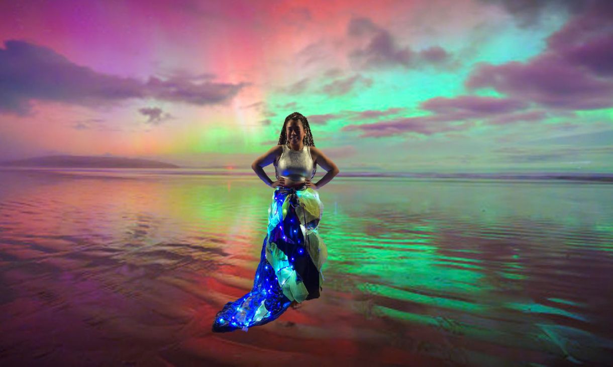 Student dressed in brightly lit clothes with aurora borealis photoshopped in background