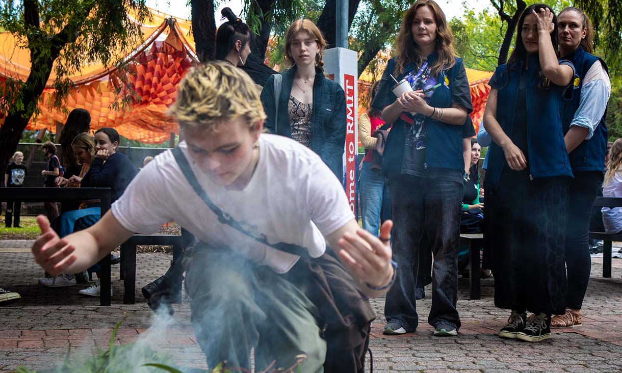 Person kneeling over smoking leaves. 