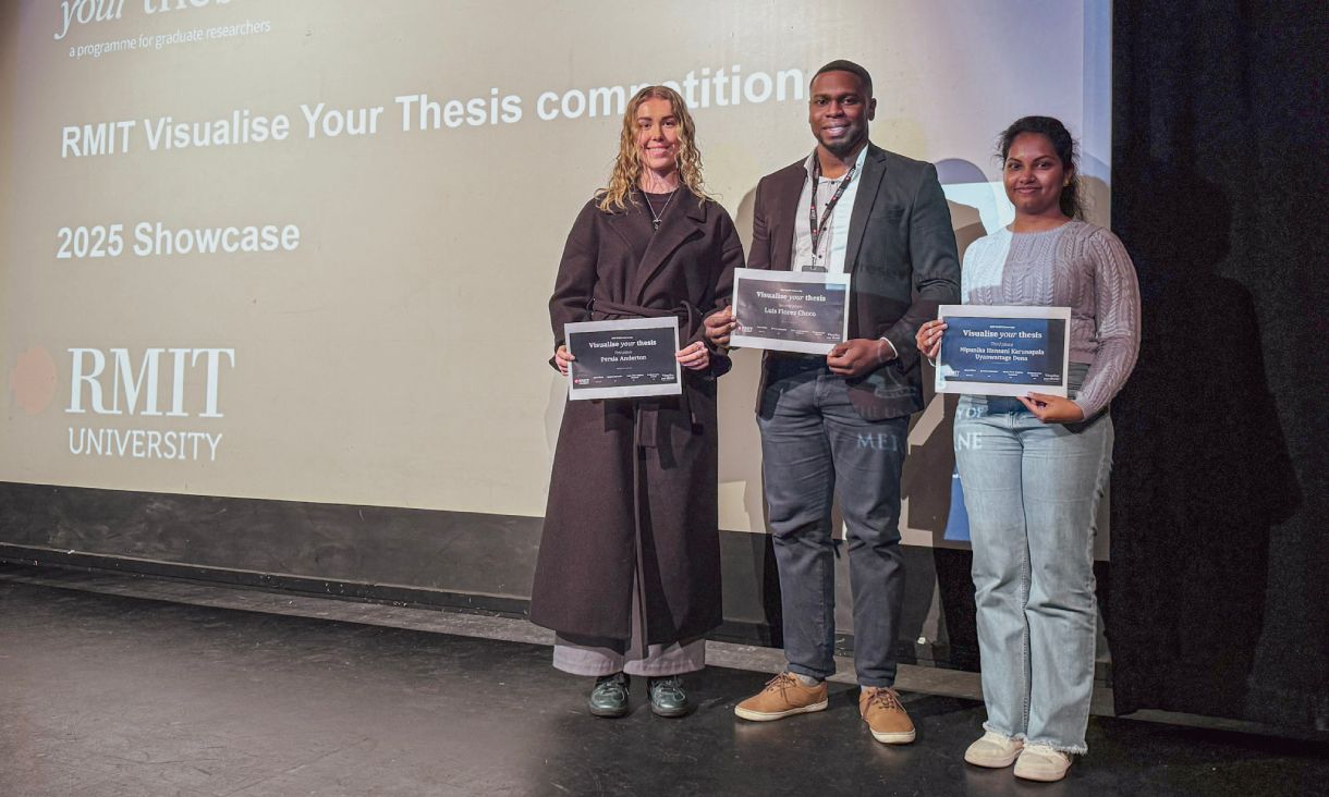 Three people standing on stage holding certificates