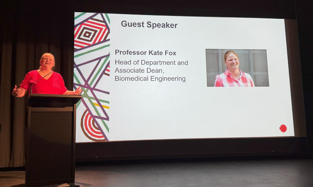 Kate Fox standing on stage addressing audience