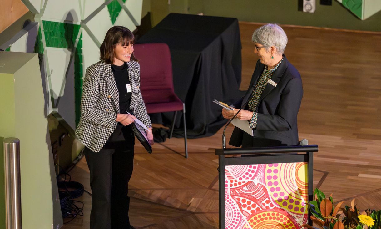 Lucinda is being presented with an award by a woman