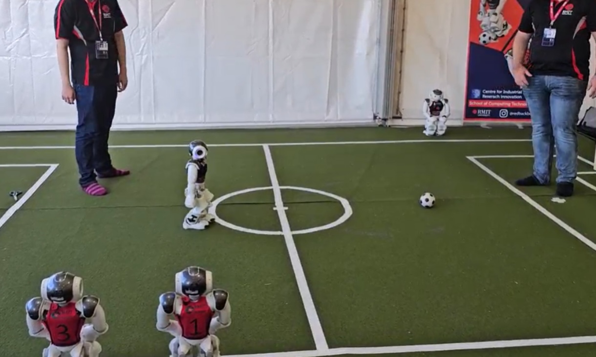 Small robots play soccer on a pitch.