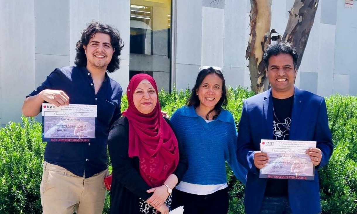 Four people standing in a row posing for a photo.