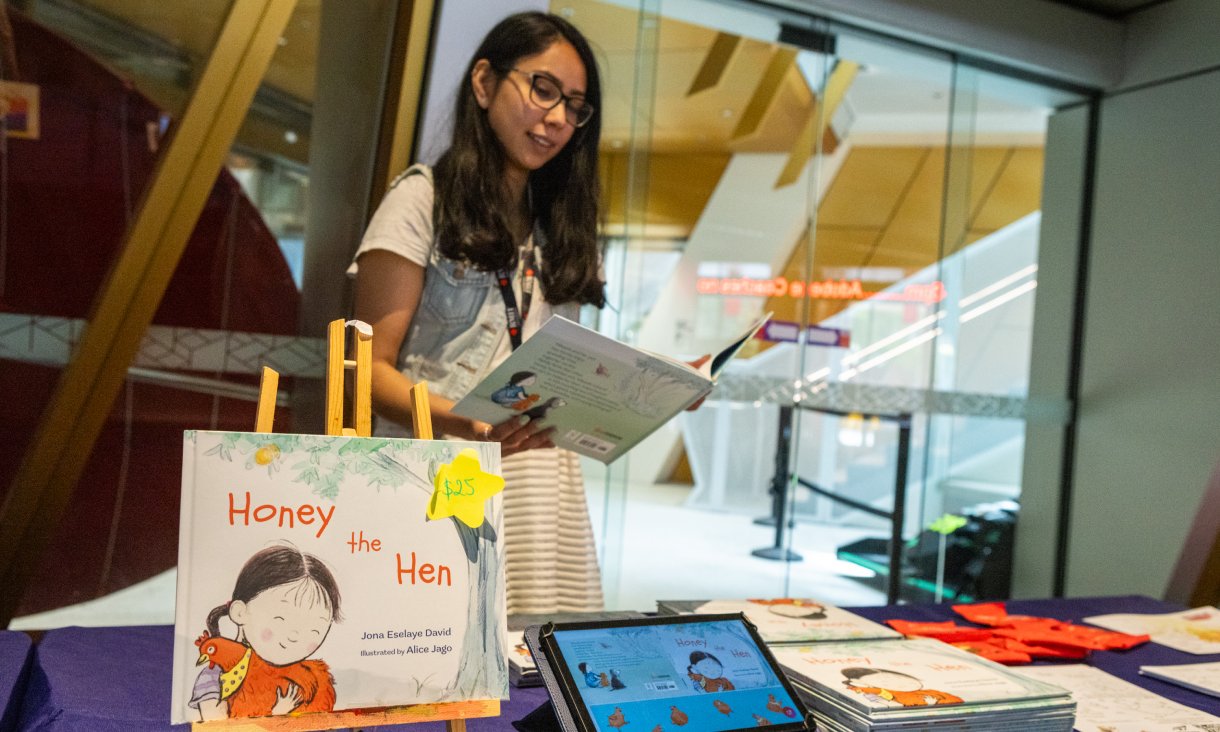 Person standing behind desk holding book