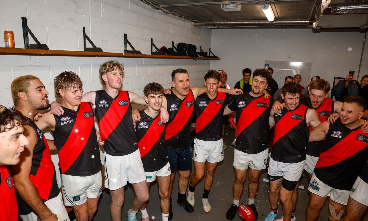 Essendon Football team standing in circle in locker room