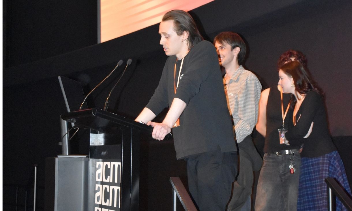 People speaking at lectern on stage