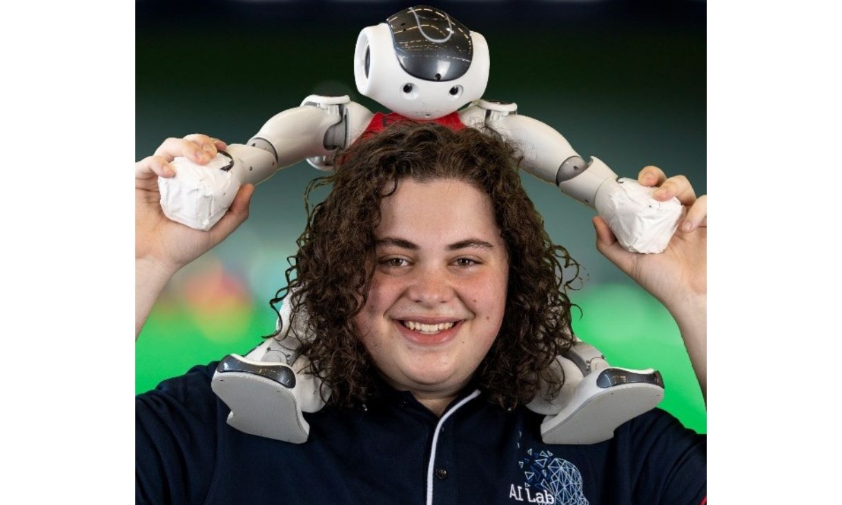 Student smiling while holding robot on shoulders