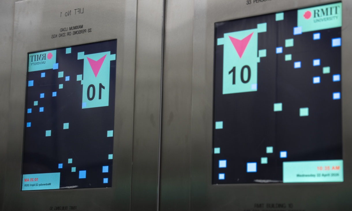 Two lift screens inside Building 10 at RMIT displaying graphic elements from Artificial Intelligelism, including coloured pixel patterns and floor indicators.