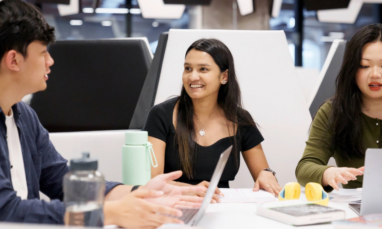 Three students sit around a table in RMIT's City Campus Library.