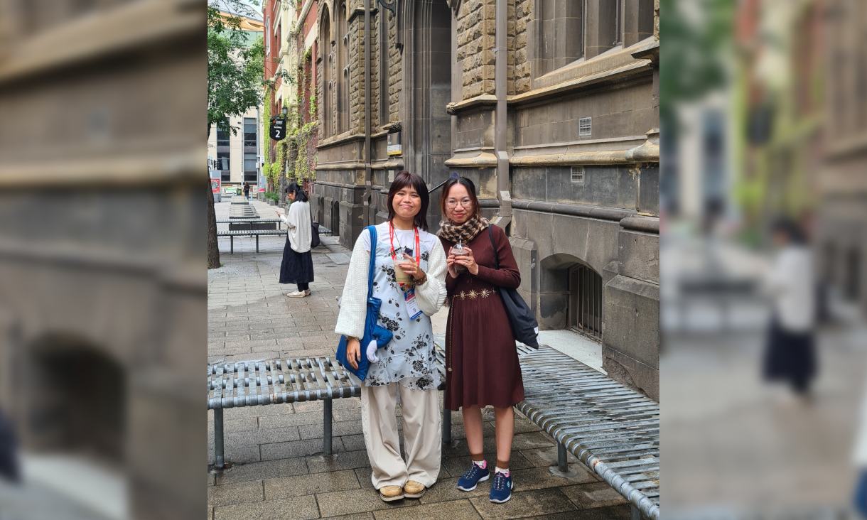 Quyen Nguyen and Thao Cao Uyen smiling with drinks outside Building 2 on RMIT’s City campus.