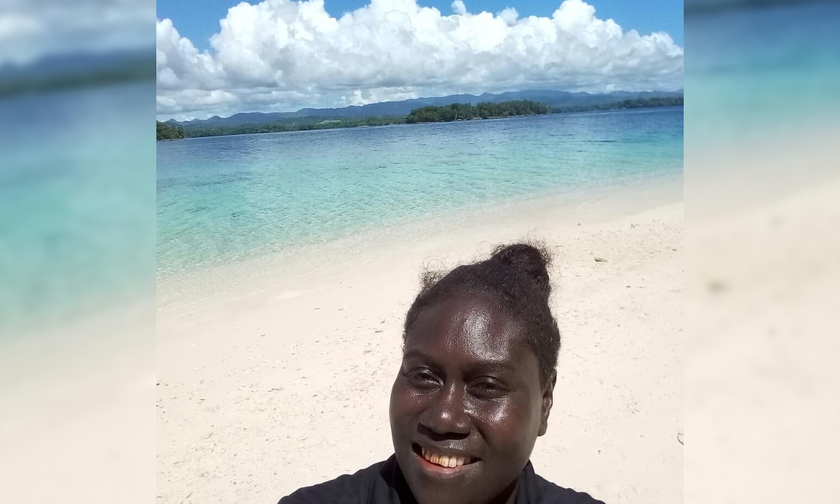 Claire standing on a beach with white sand and blue water