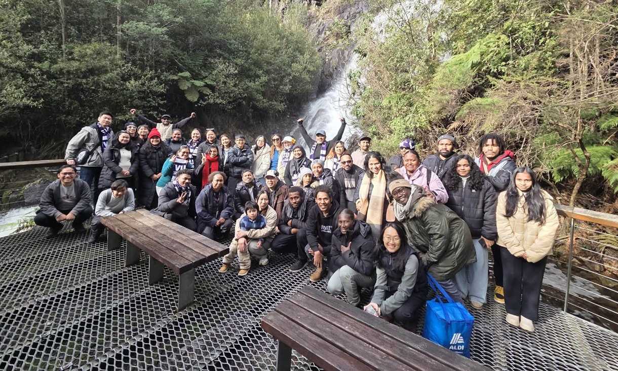 Students posing in group in front of waterfall