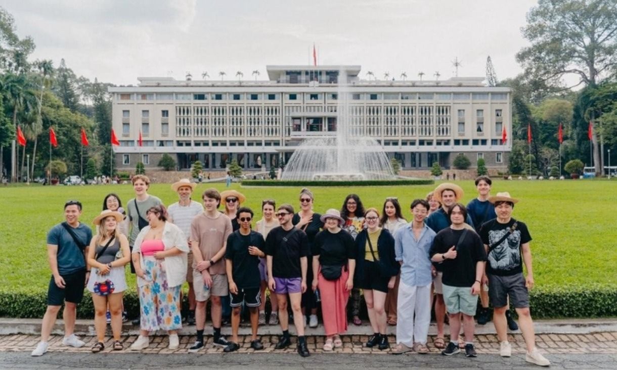 Students on a lawn standing in front of a white building in Vietnam