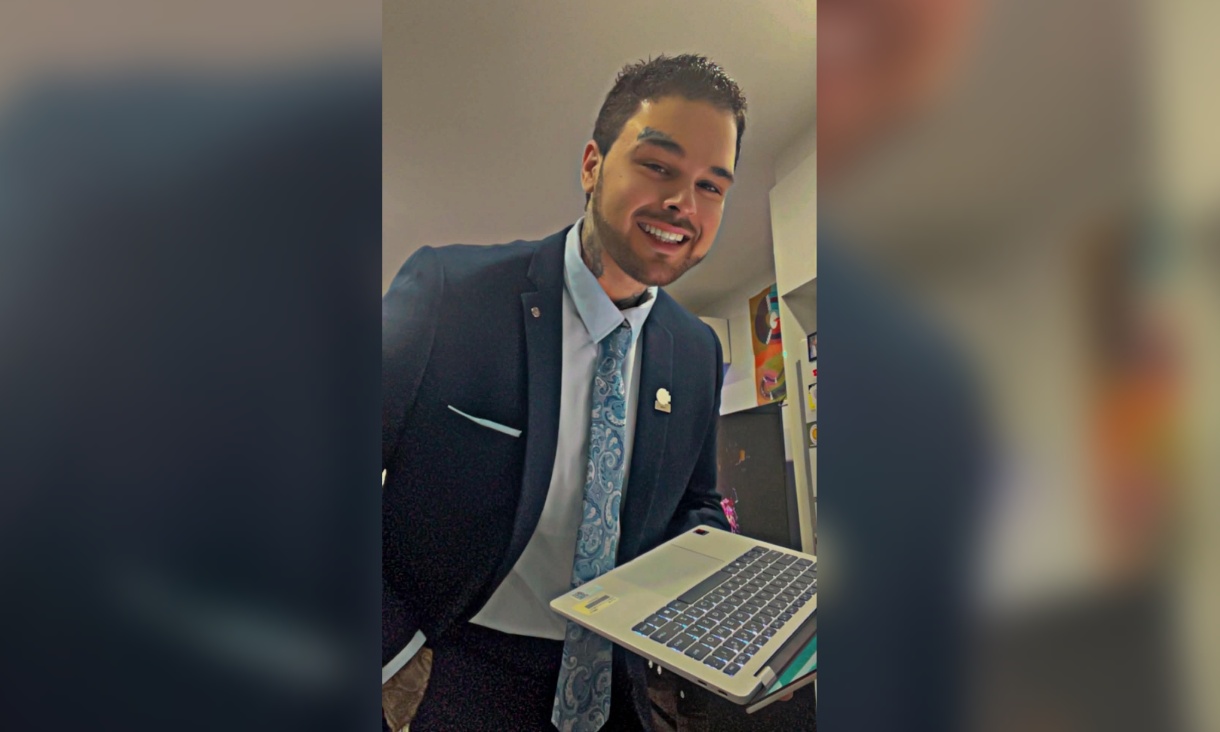 Dillon Stocks in a suit and tie holding an open laptop