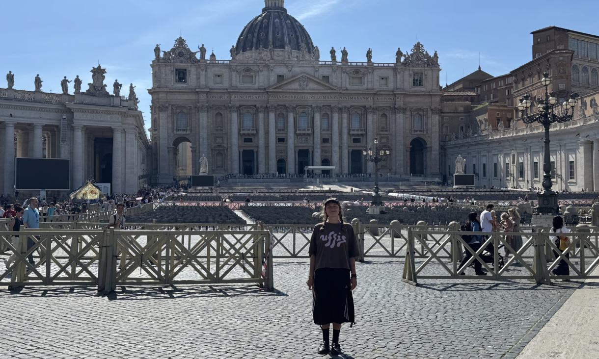 One person standing in St Peter’s Square with the façade and dome of St Peter’s Basilica in the background.