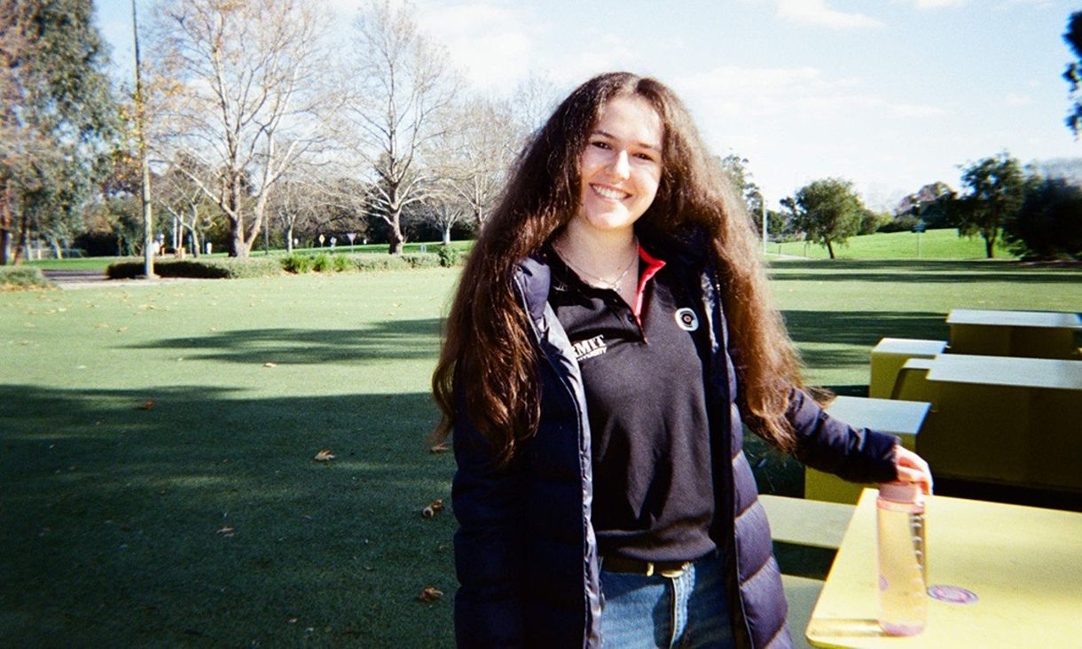 Felicity standing outside next to table wearing RMIT jacket