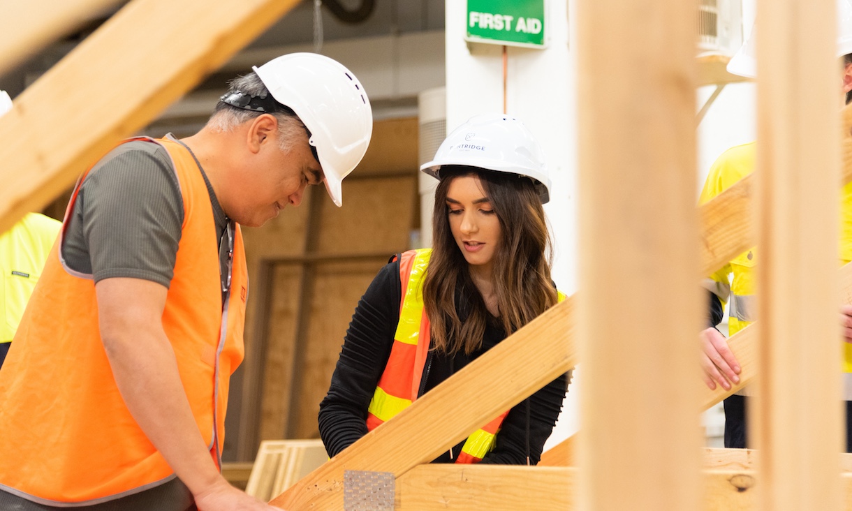Apprentice wearing a hard hat learns how to build something.