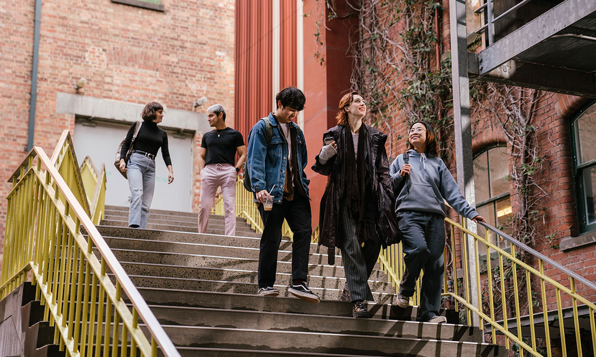 A student smiles as she hangs a painting of a hand on a peg line