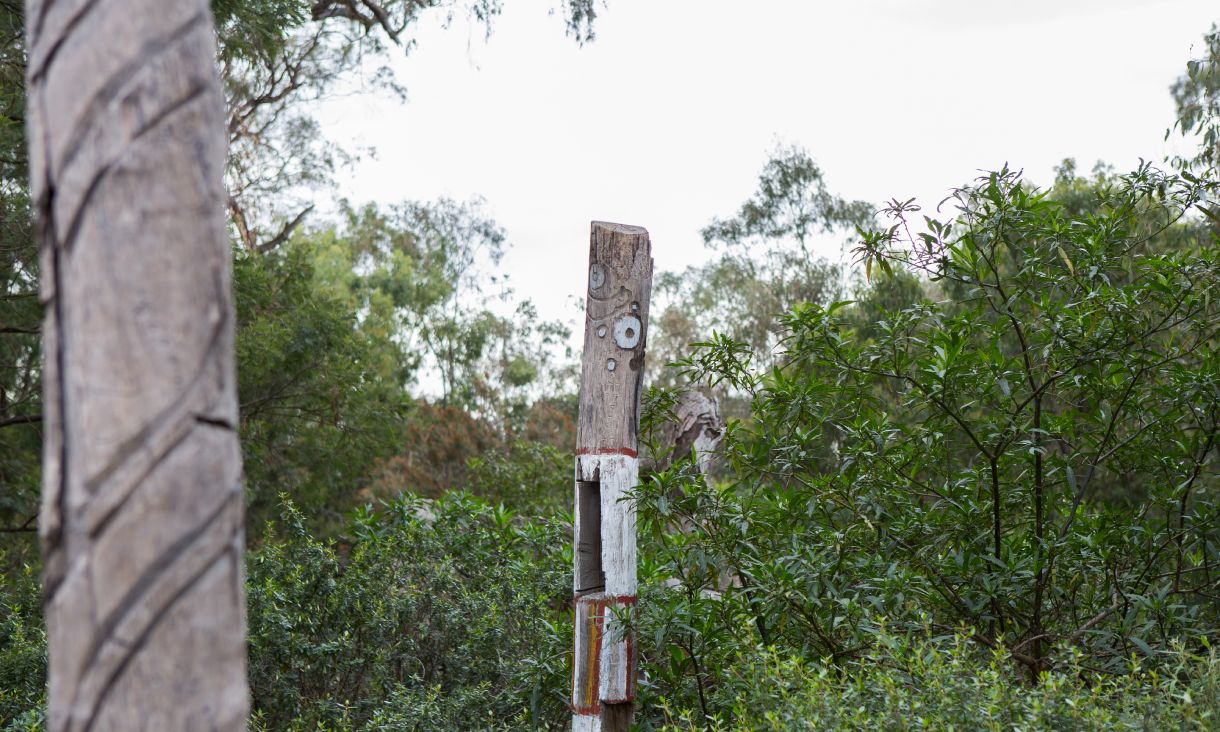 Wooden pole in forest with indigenous artwork
