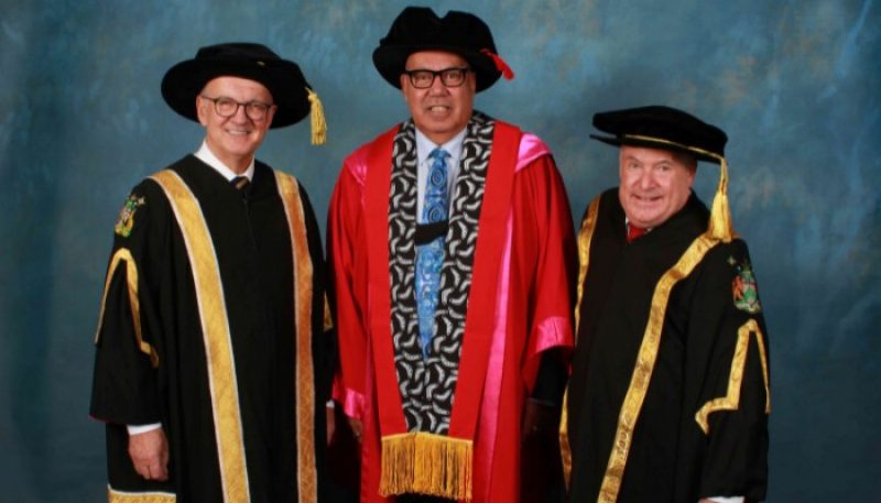 Leaders of RMIT stand wearing graduation dress.