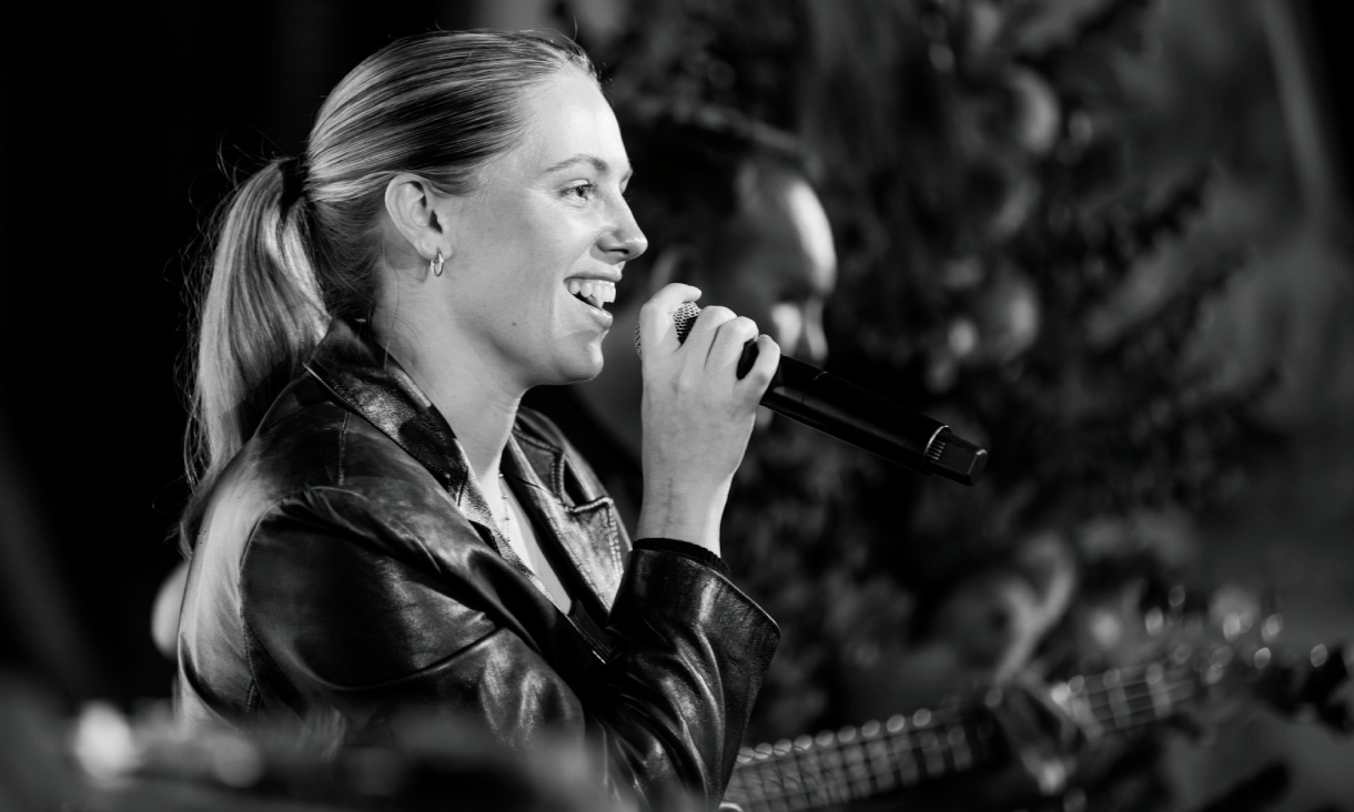 Black and white photo of Canisha Clemmet-Kennedy smiling and holding a microphone.