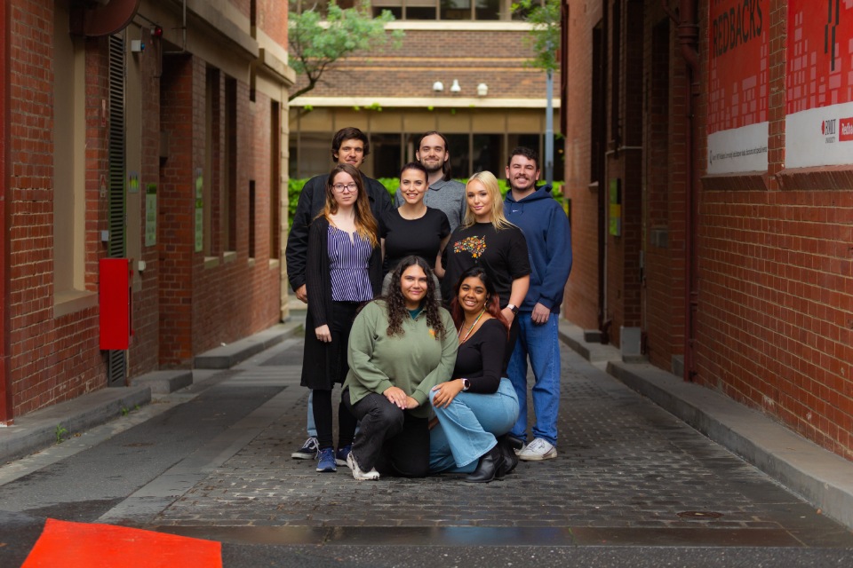 Eight people smiling at camera standing on street