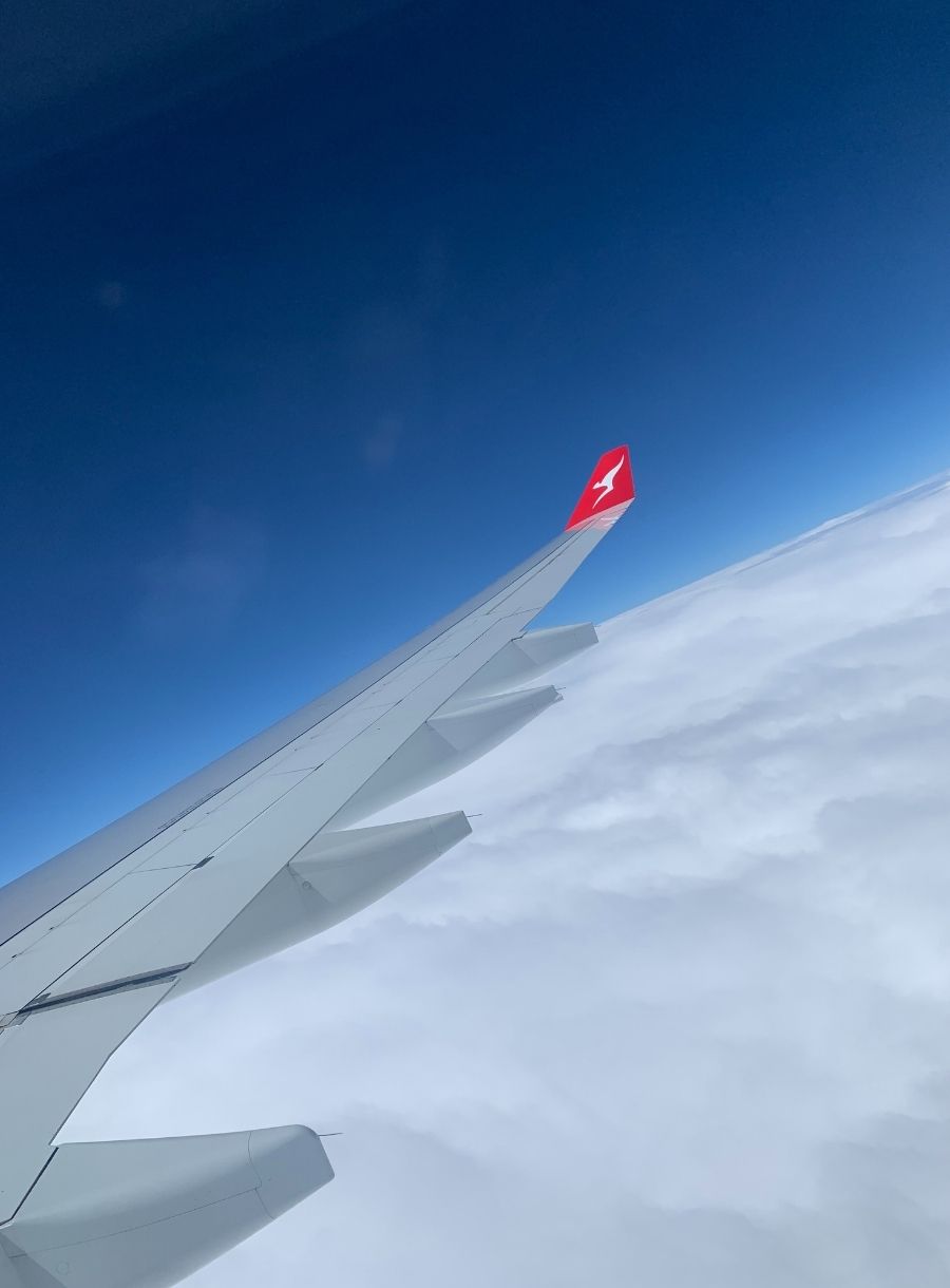 A wing of a QANTAS plane in the air.