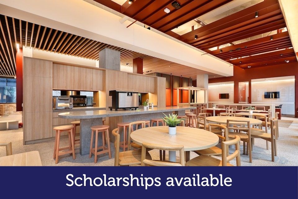 Open space with wooden furniture. The words 'Scholarships available' is printed on the photo.