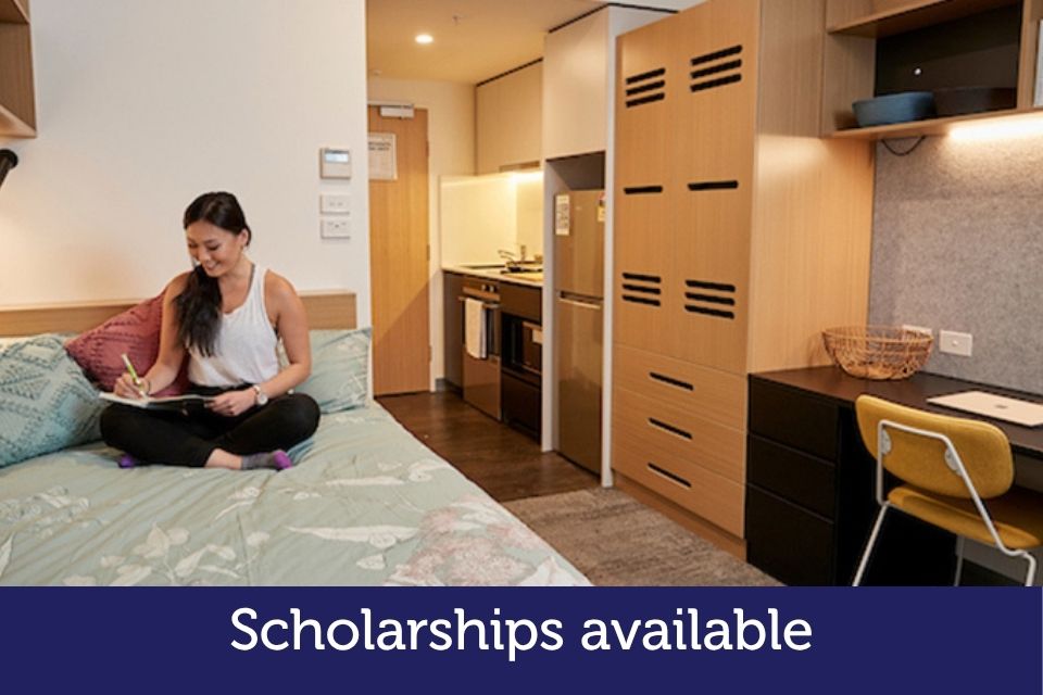 A female student studies on her bed in an apartment.