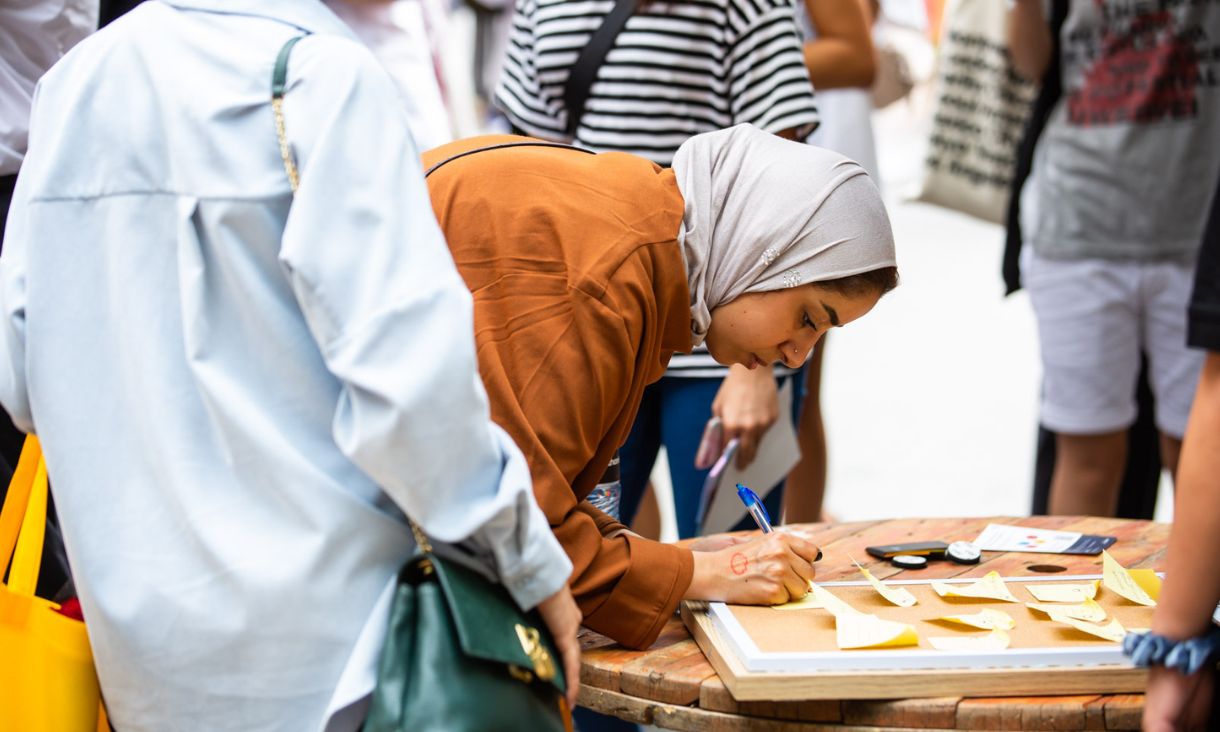 A student bending down to write something on a post-it.