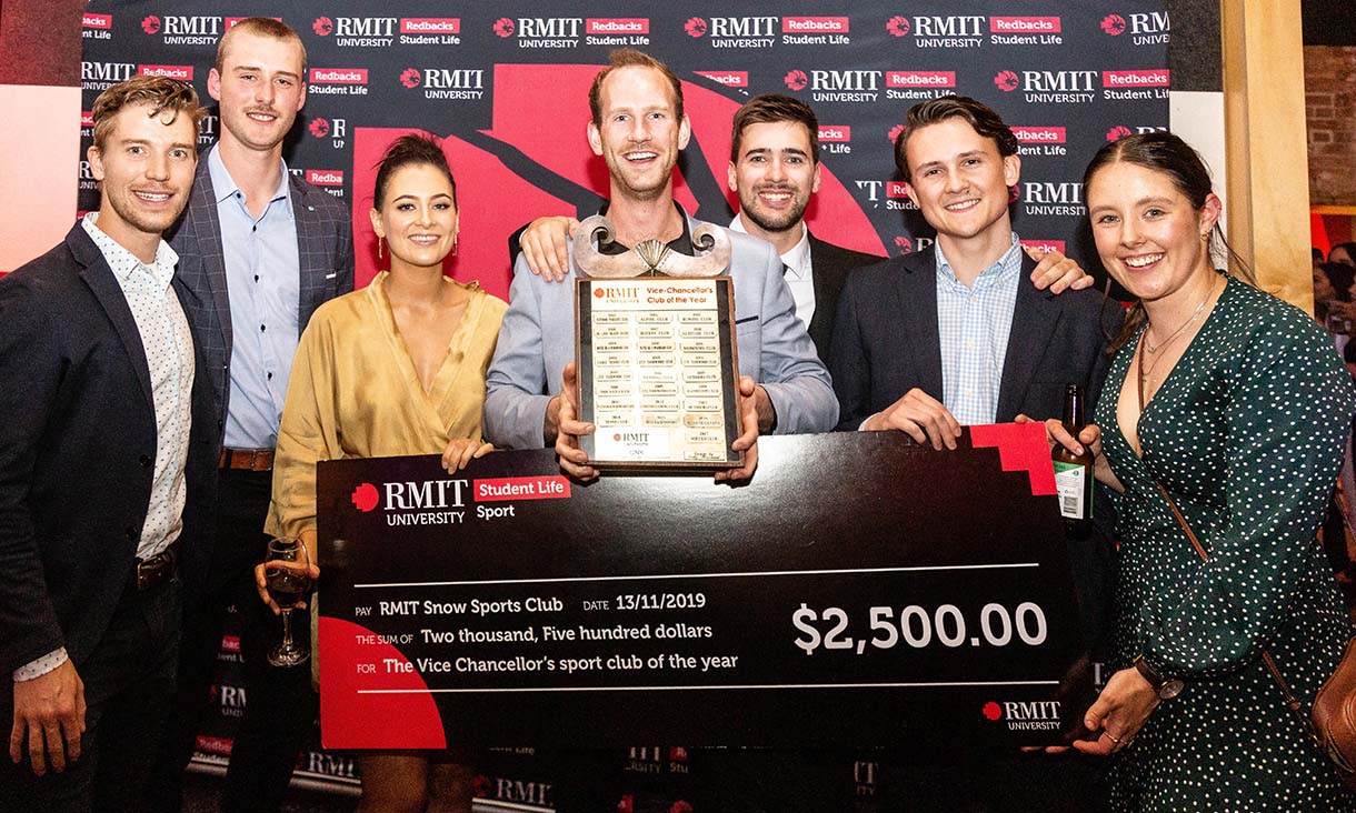 A group of people holding a plaque and a novelty check. 
