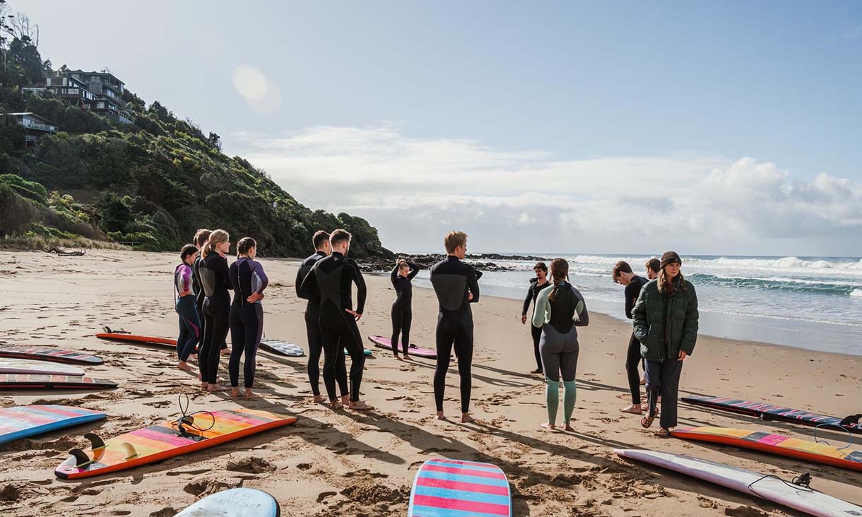 Surf club on the beach in a circle, surf boards on the sand.