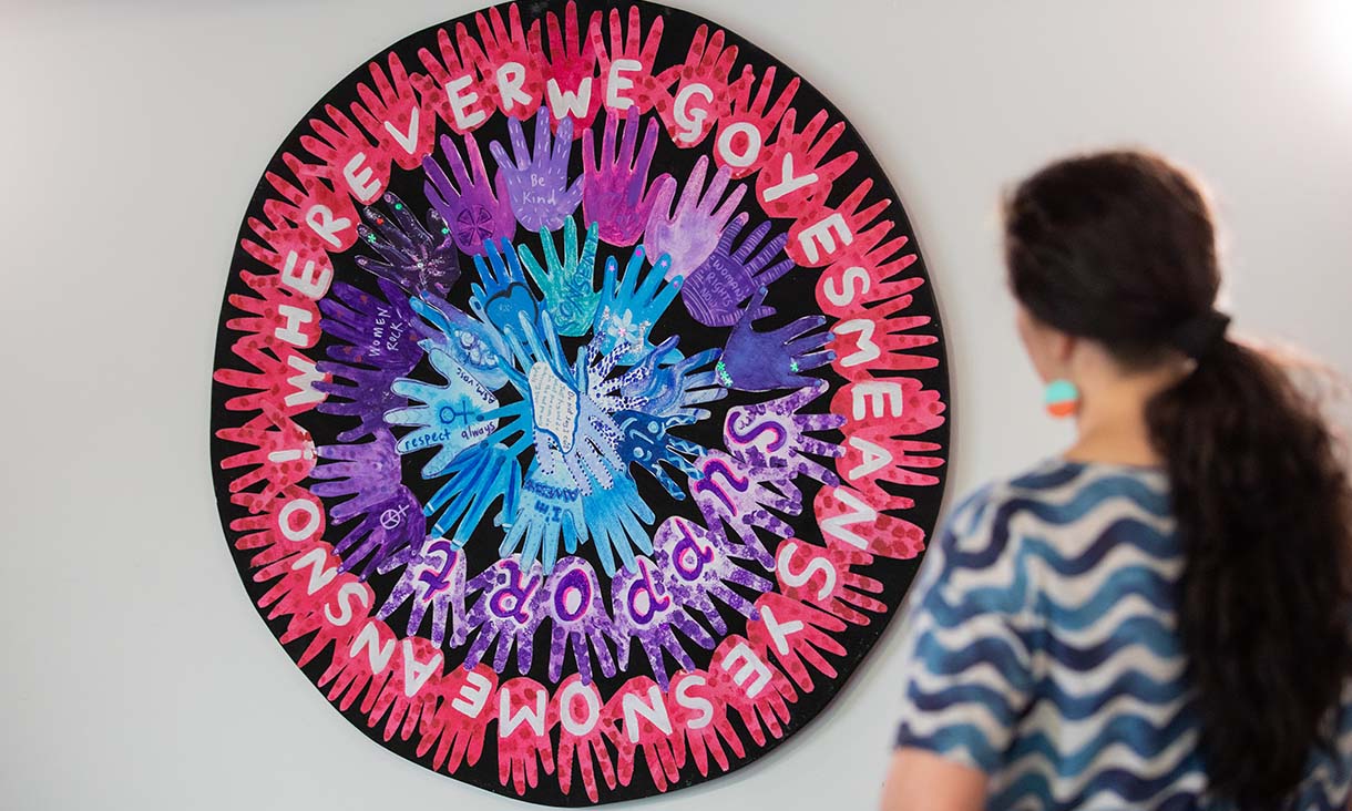 Colourful hands form the shape of a woman on a black background.