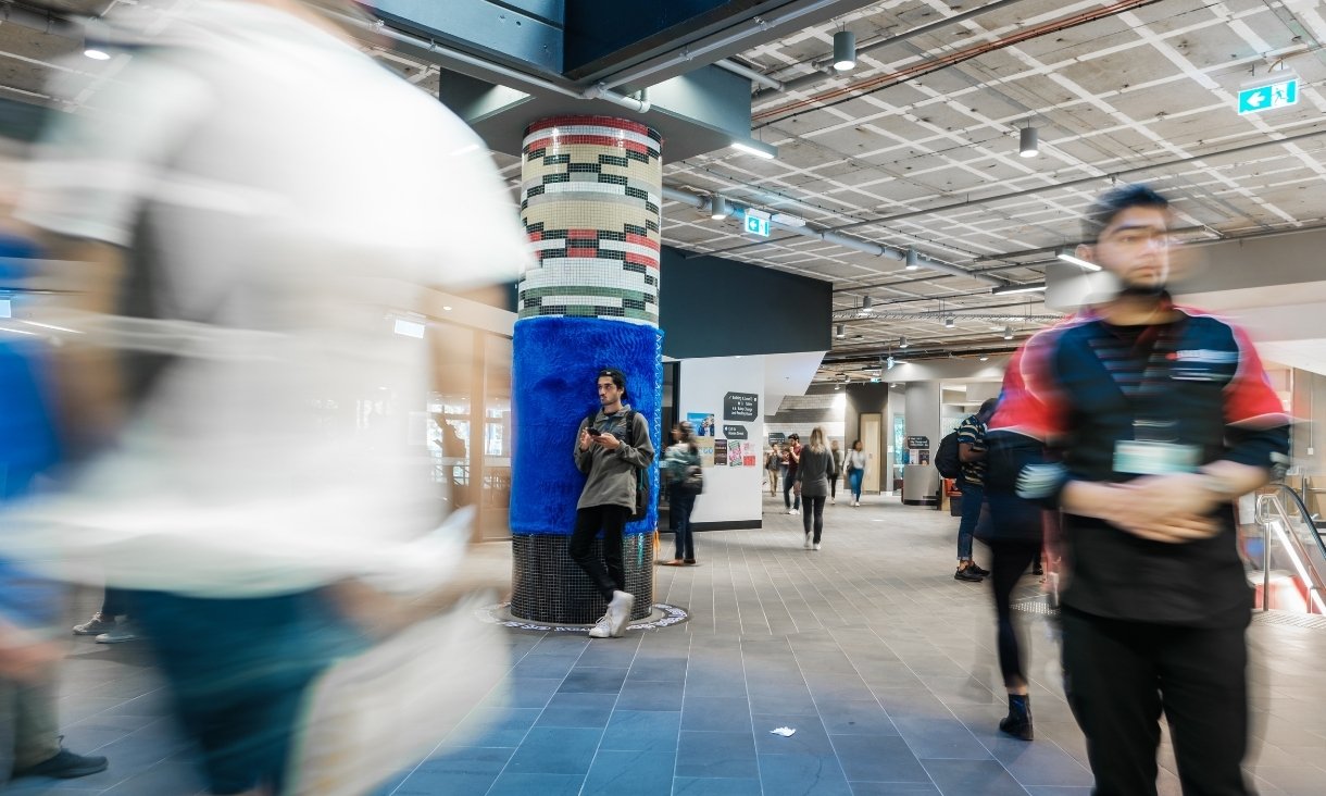 People walking past blue fluffy pole