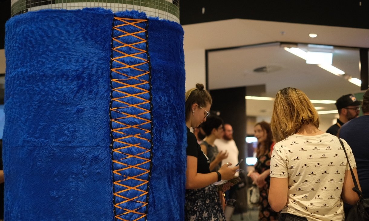 People leaning against blue fluffy pole