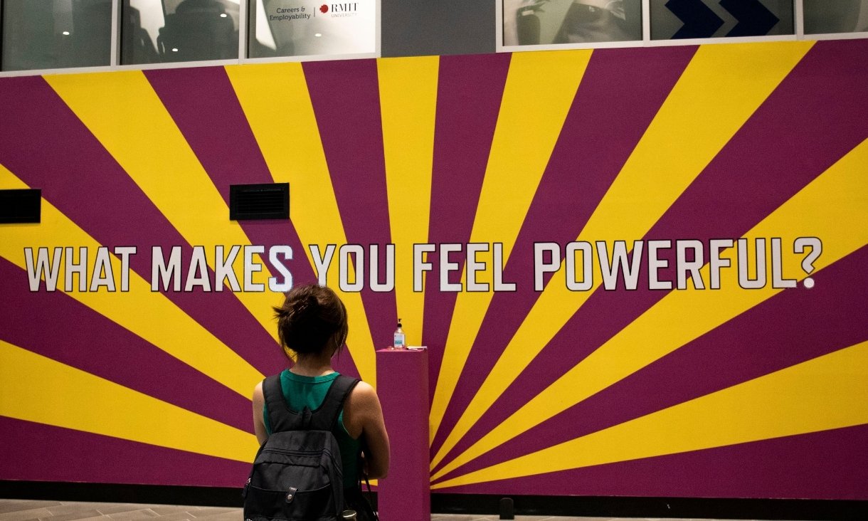 Person looking at text on wall 'What makes you feel powerful?'