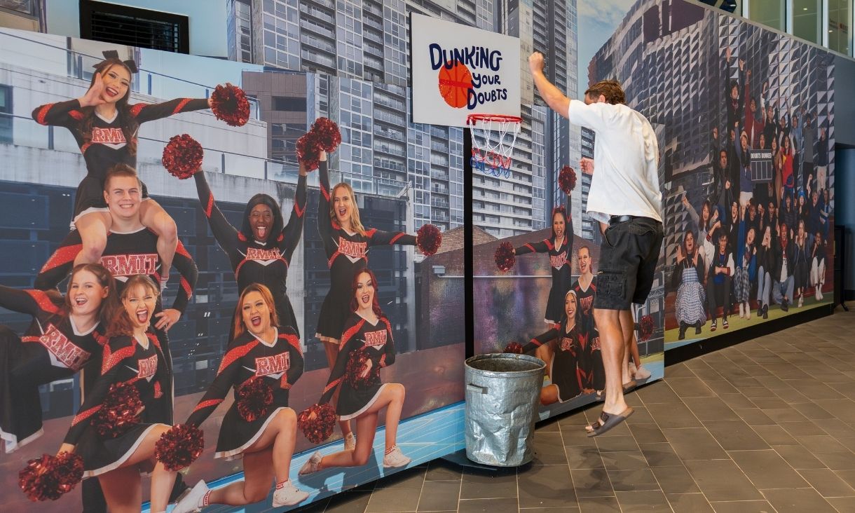 Person throwing paper into basketball hoop into bin
