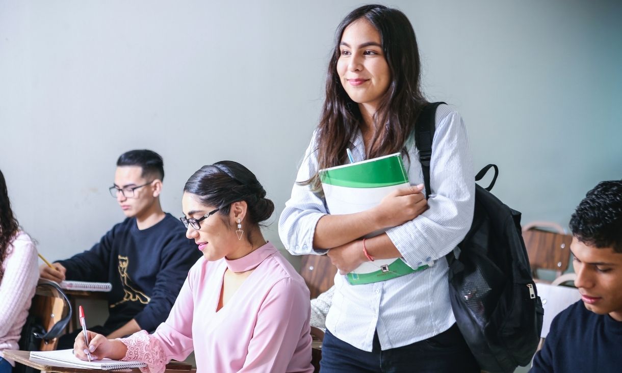 Smiling woman carrying books and a backpack