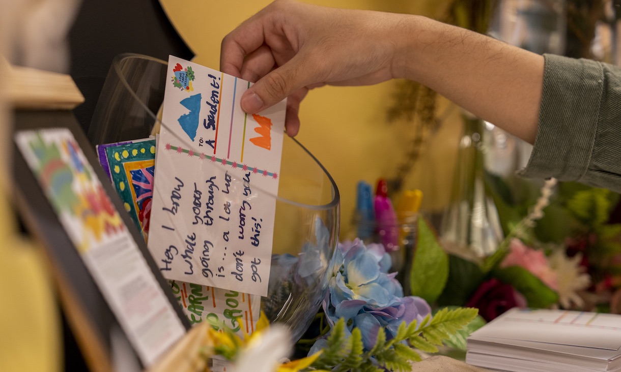 Hand places a colourful affirmation message in a glass bowl