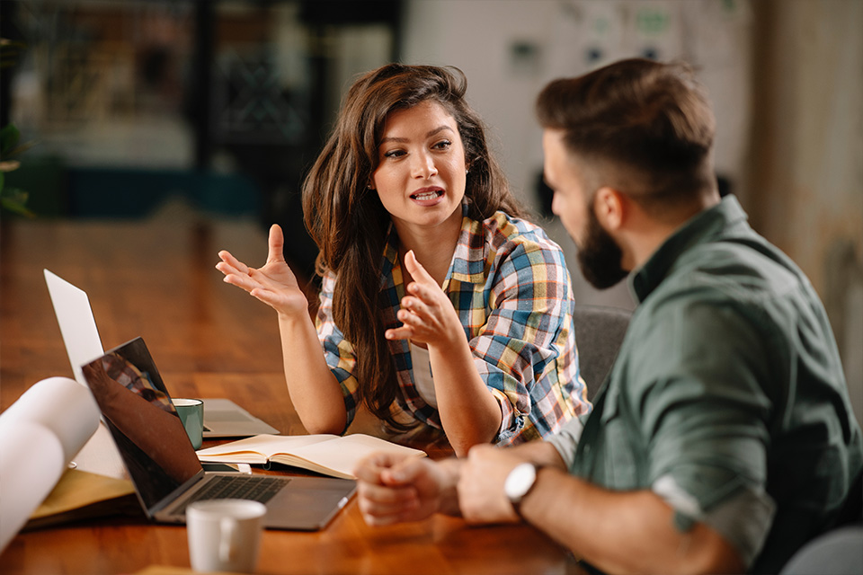 Two people at a desk in discussion with eachother.