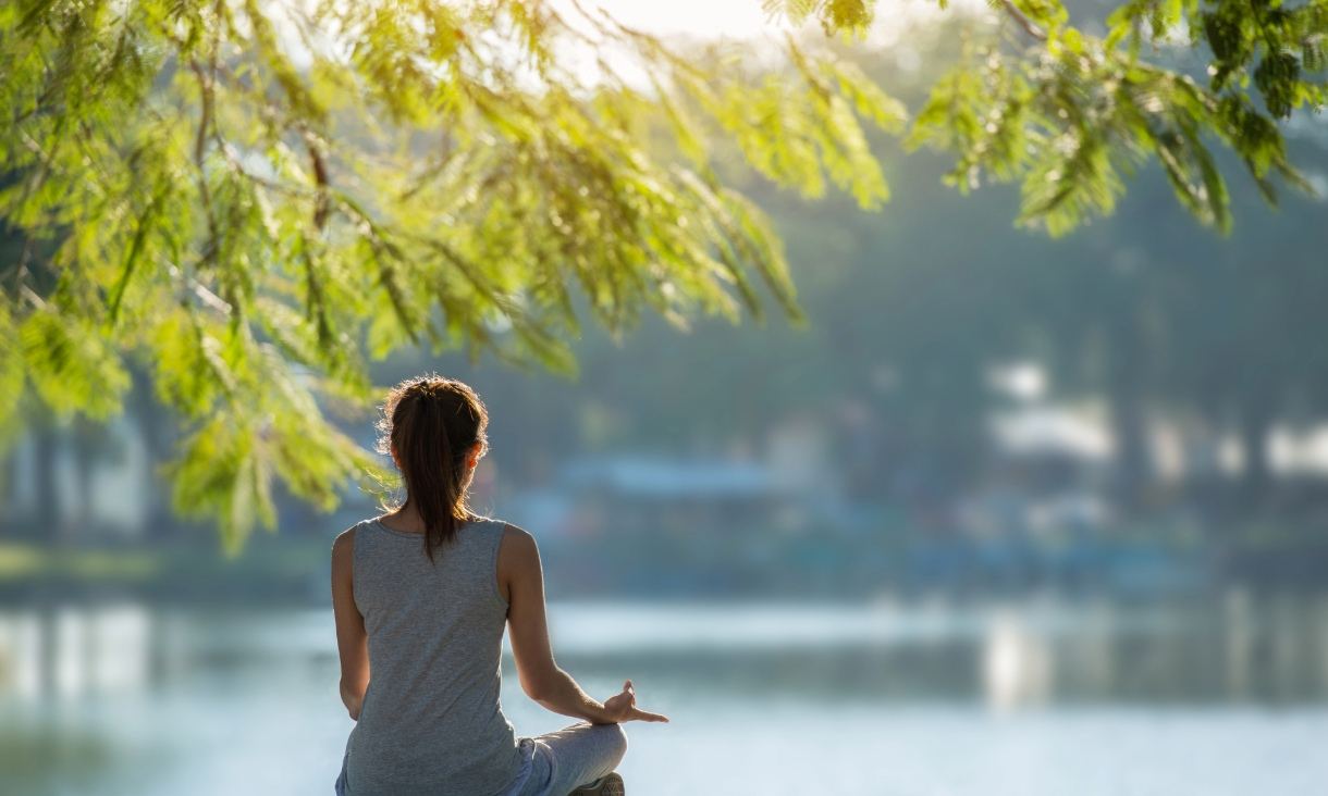 Woman meditating in front of lake