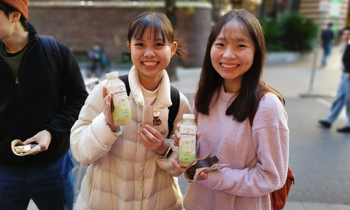 Two people holding apple juice smiling