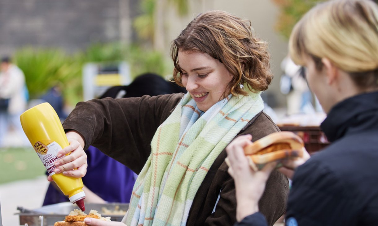 Person using mustard holding vegan burger