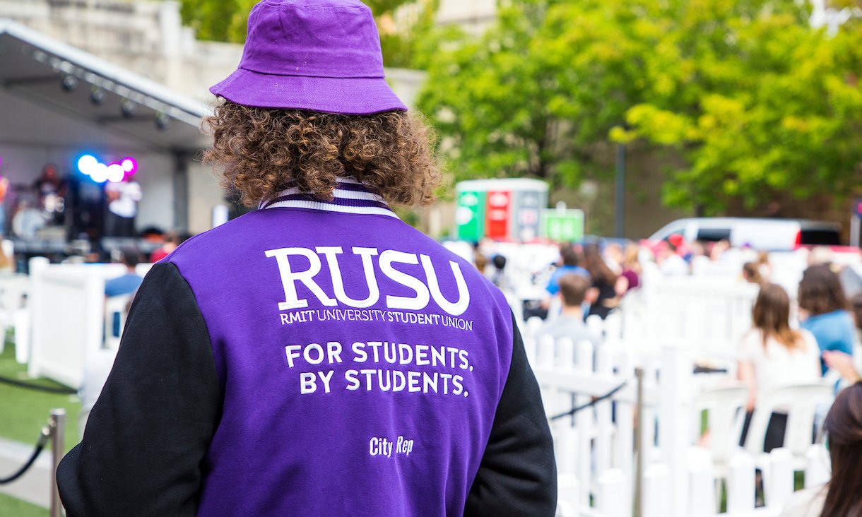 Person wearing purple bucket had and RUSU jacket