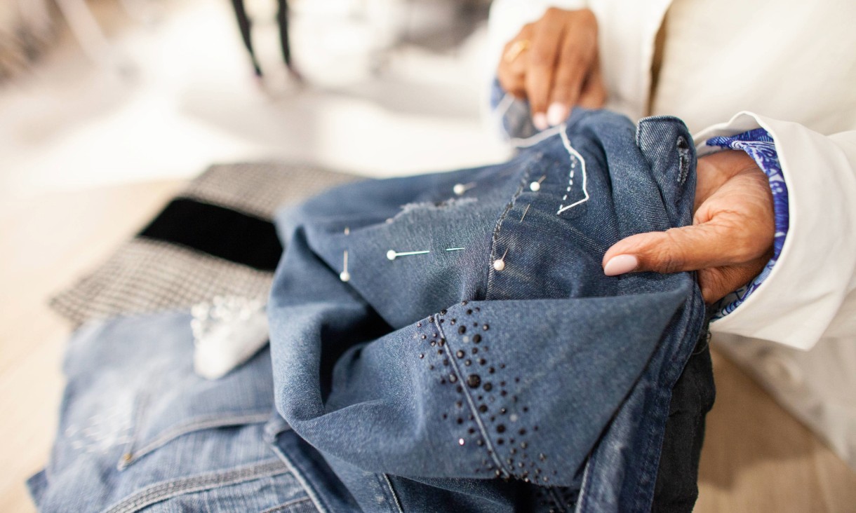 Person sewing blue denim jeans by hand.